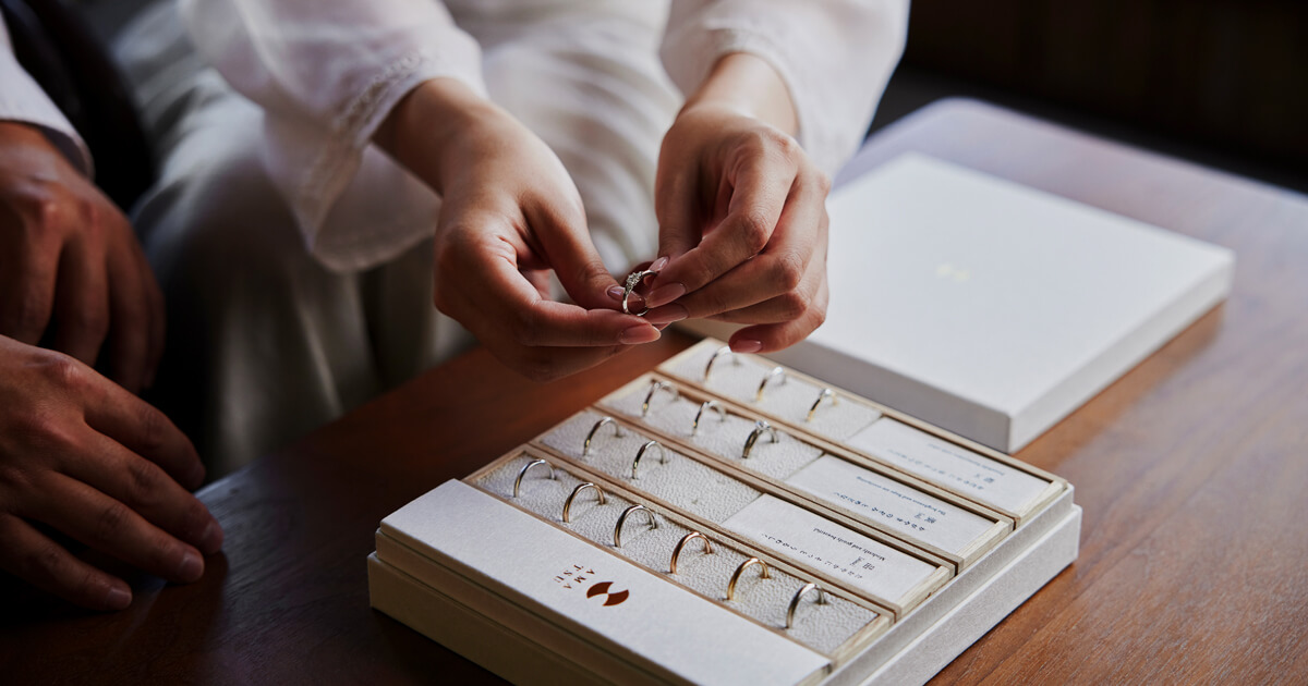 AMATSUのサンプルリングを手に取り、おふたりで結婚指輪を選んでいる様子