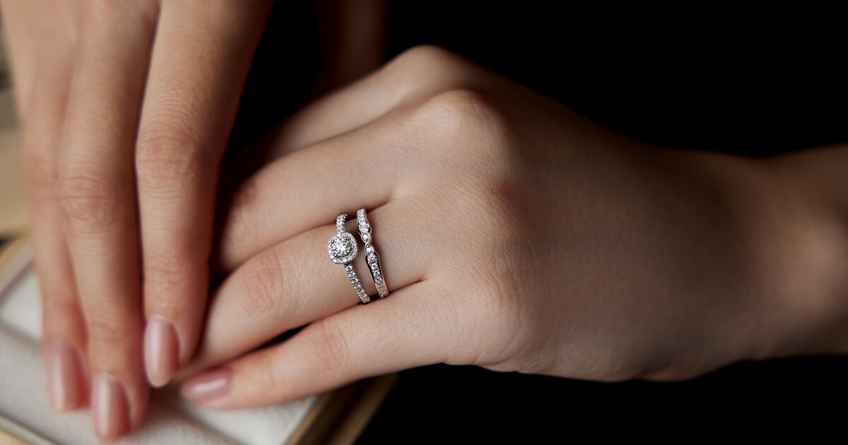 AMATSUの婚約指輪とダイヤモンドをあしらった結婚指輪を重ね着けした女性の手元