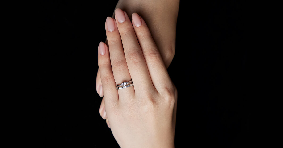 AMATSU「宮 -miya-」の婚約指輪と結婚指輪の重ね着け。ダイヤモンドが輝く婚約指輪と、やわらかな曲線を描くプラチナの結婚指輪が美しく調和するブライダルリング。