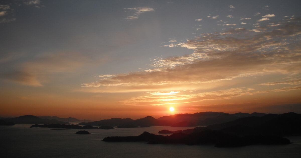 瀬戸内海に浮かぶ島々の向こうへ沈む夕日と、穏やかな海の風景